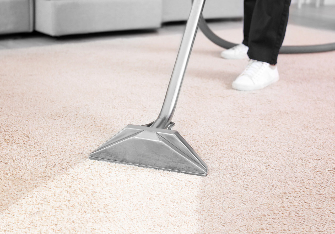 Worker removing dirt from carpet indoors, closeup. Cleaning service